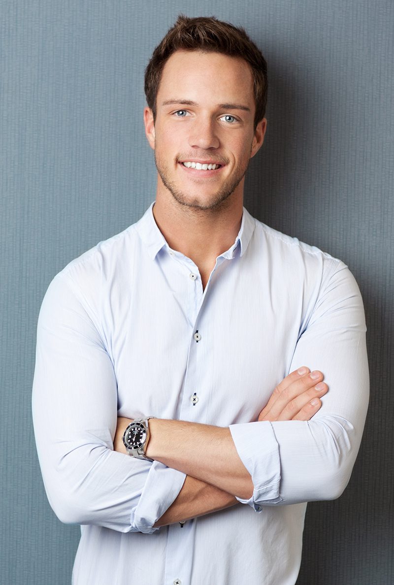 A man with his arms crossed wearing a white shirt.