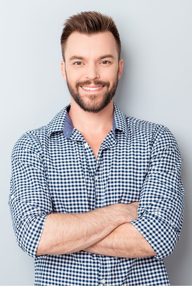 A man with his arms crossed wearing a plaid shirt.