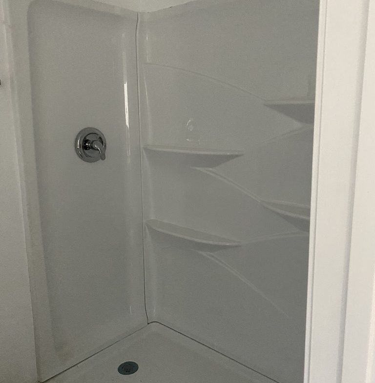 A white shower with shelves and a black handle.