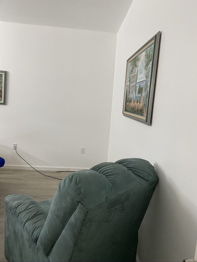 A green chair in the corner of a room.