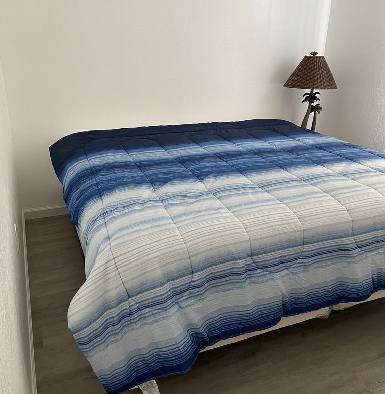 A bed with blue and white comforter on it.