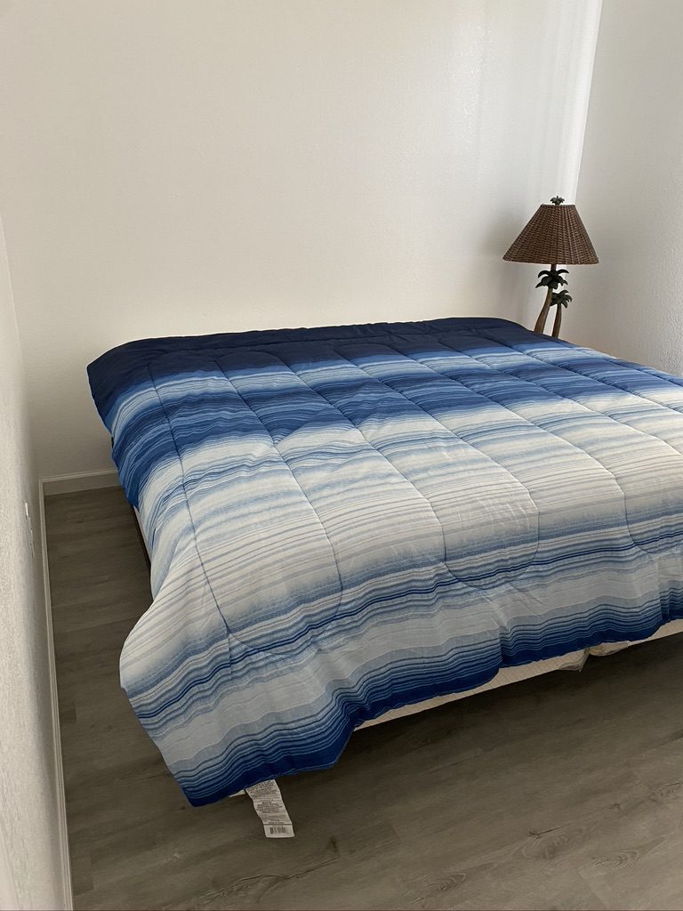 A bed with blue and white comforter on it.