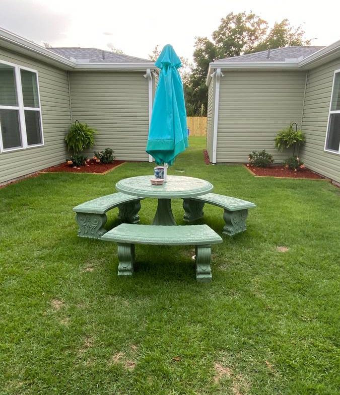 A green table and bench set in the middle of an enclosed yard.