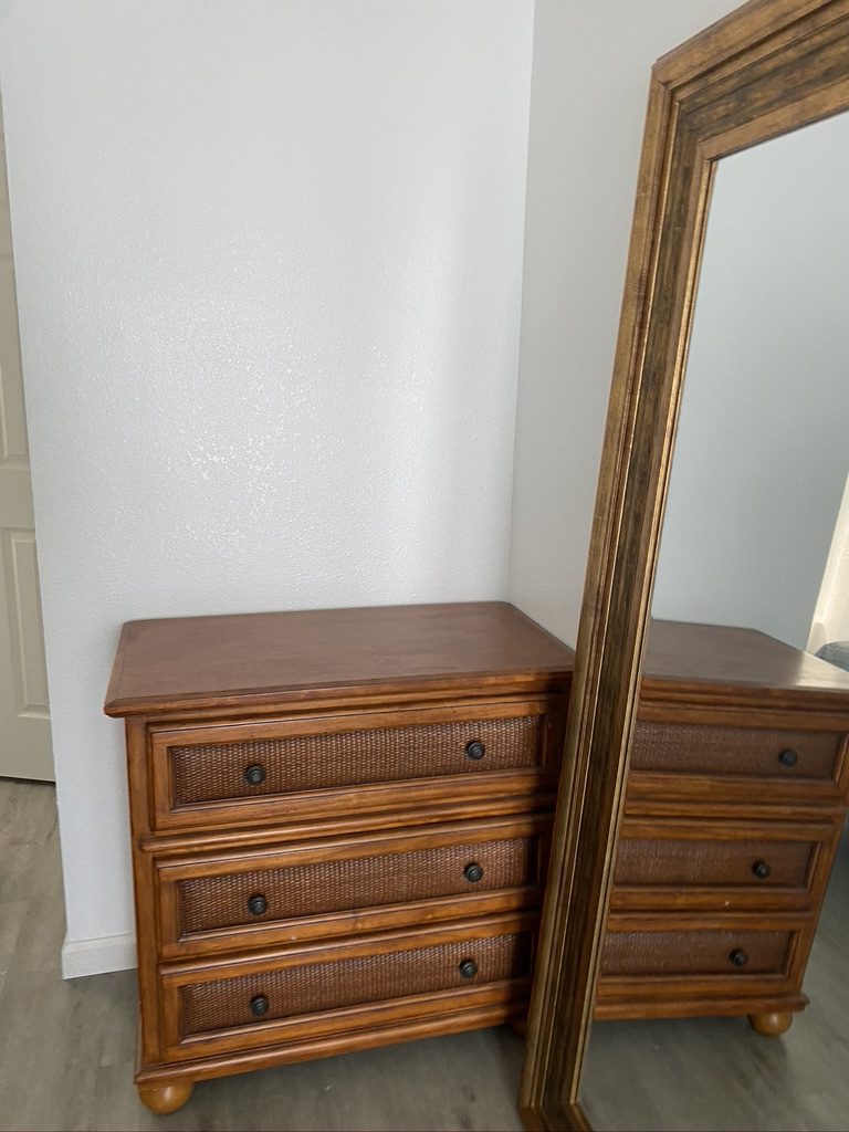 A dresser and mirror in the corner of a room.