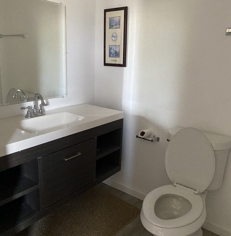 A bathroom with a sink, toilet and mirror.