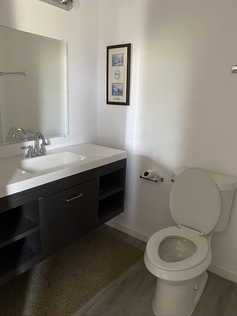 A bathroom with a sink, toilet and mirror.