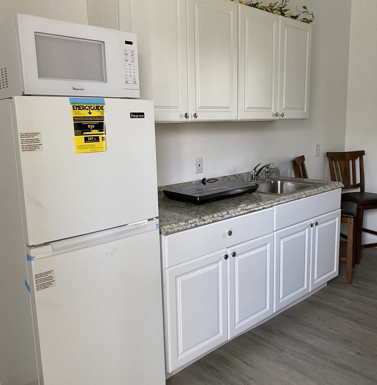 A kitchen with white cabinets and appliances.