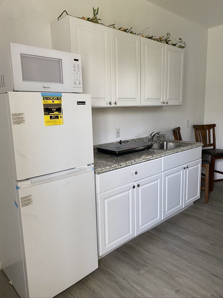 A kitchen with white cabinets and appliances.