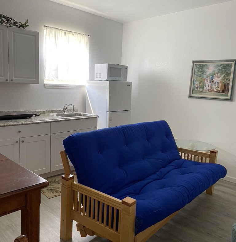 A blue futon in the living room of a small apartment.