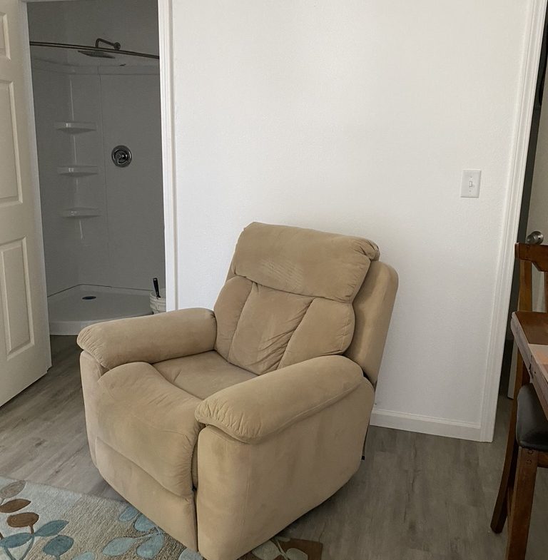 A chair in the corner of a room with a rug.