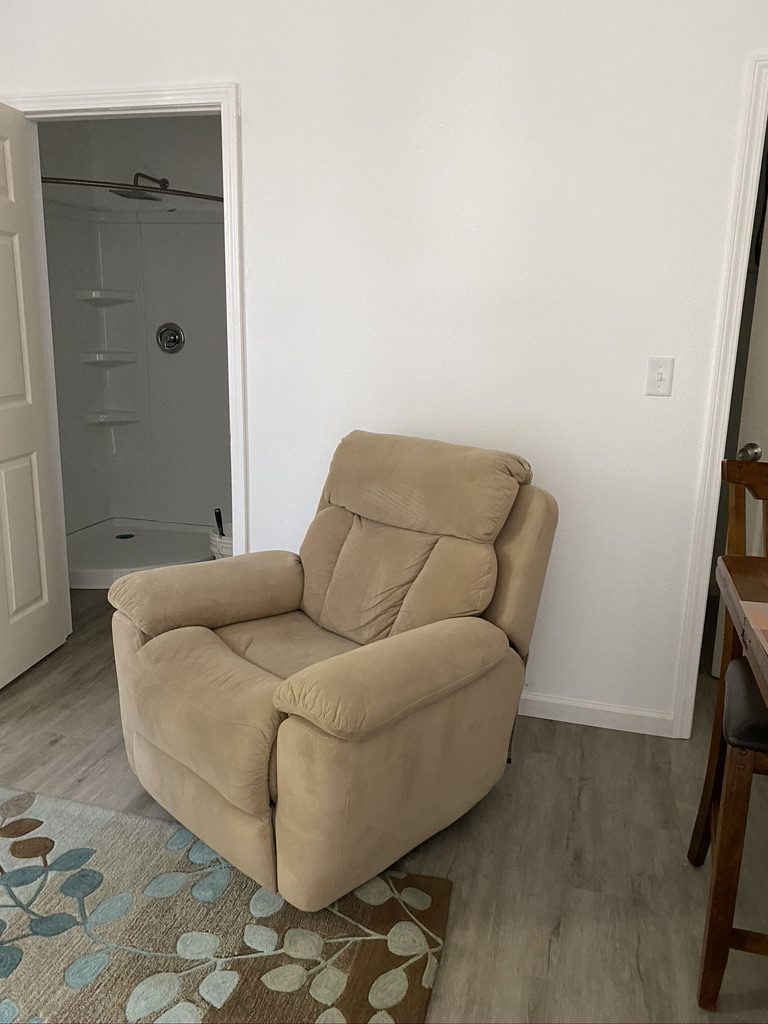 A chair in the corner of a room with a rug.