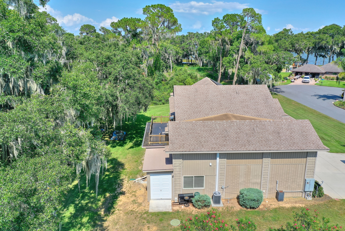 A house with trees in the background and a garage door open.