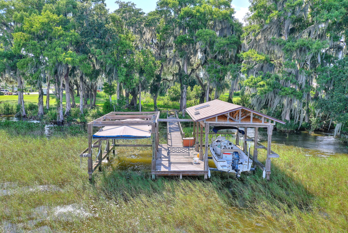 A painting of a dock with boats in the grass.