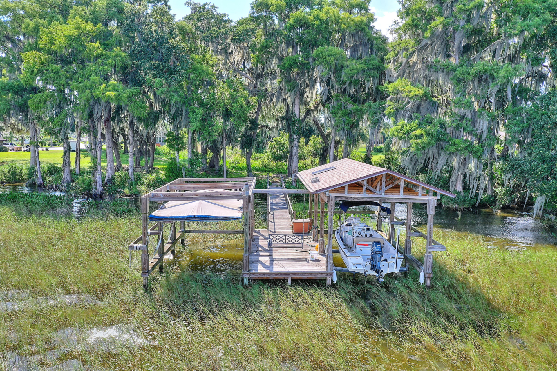 A painting of a dock with boats in the grass.