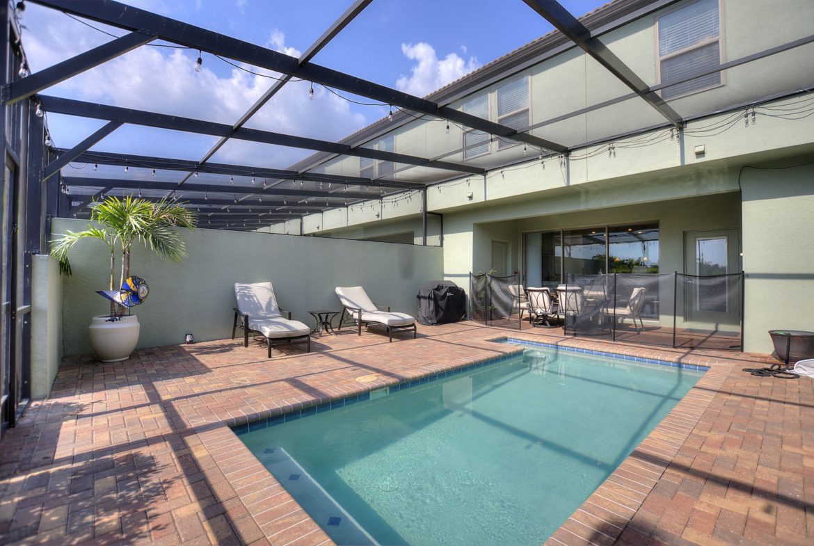 A pool with chairs and a patio cover