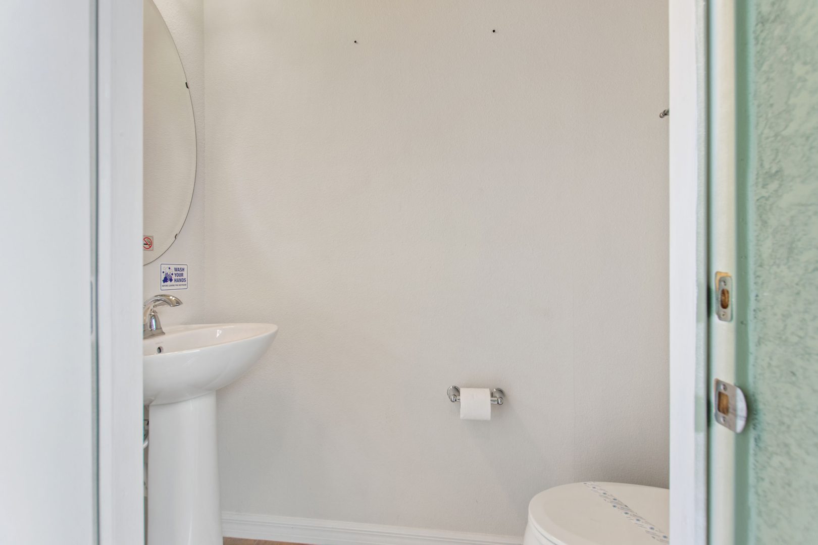 A bathroom with white walls and wooden floors.