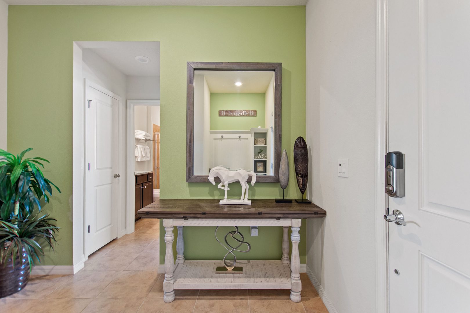 A white table with a mirror and a horse statue on it.