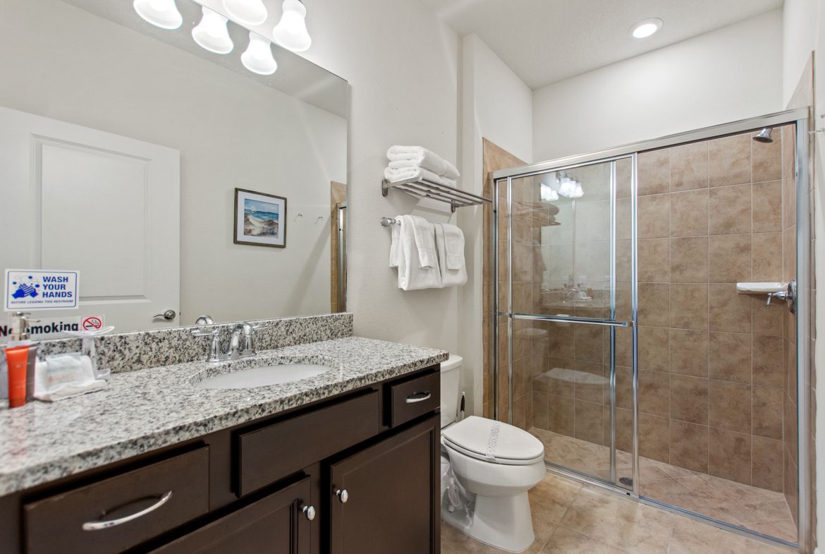 A bathroom with a shower, toilet and sink.