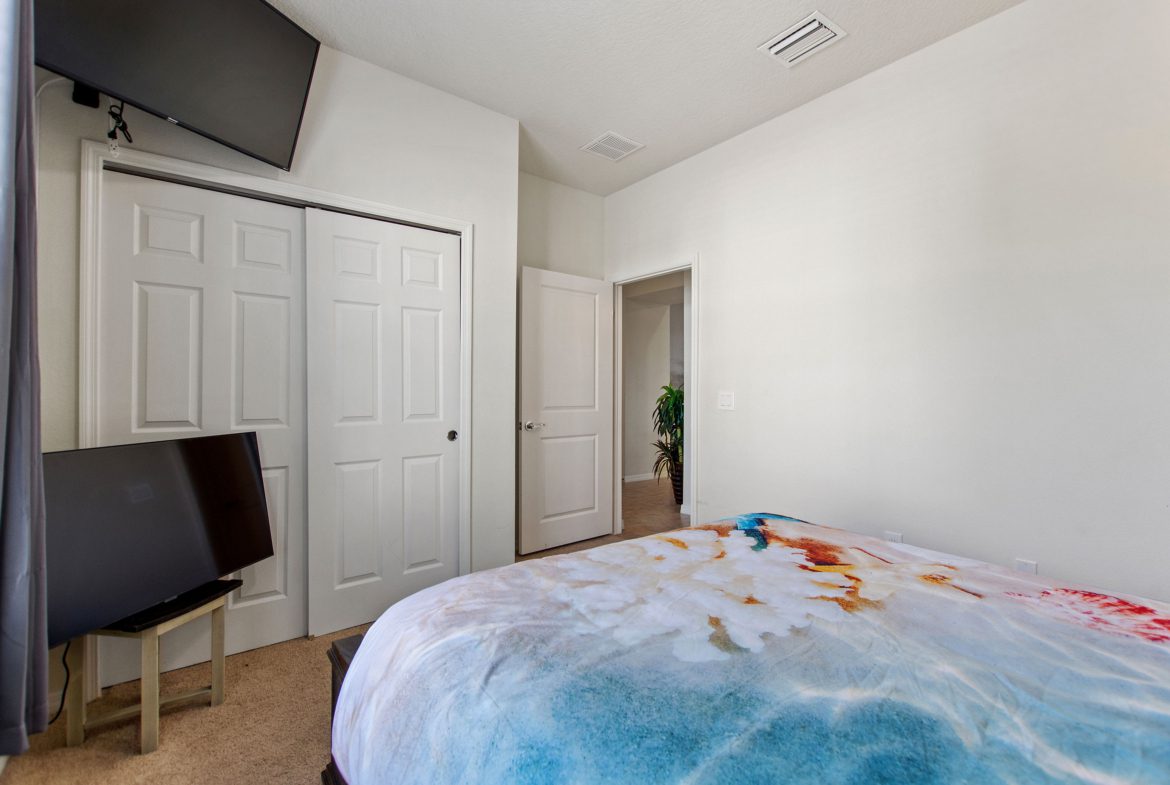 A bedroom with a bed, tv and chair.