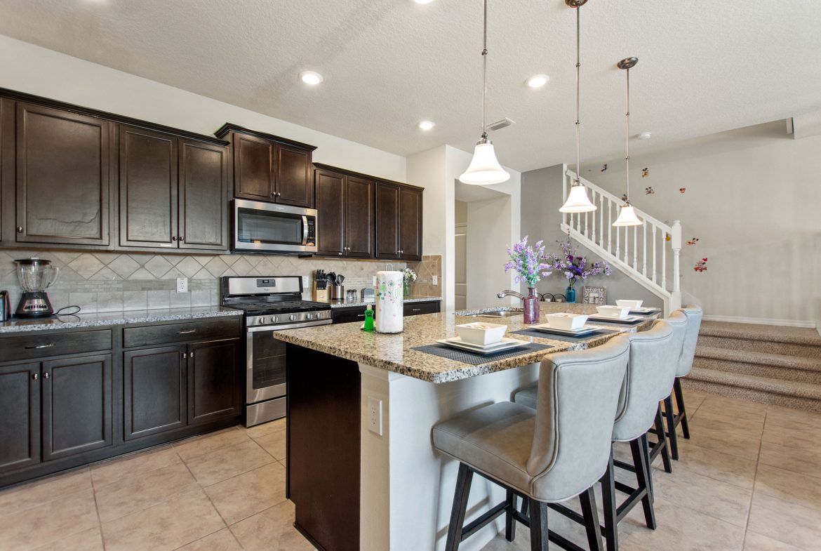 A kitchen with dark cabinets and white appliances.