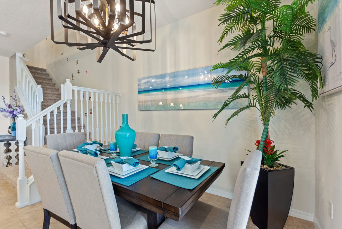 A dining room table with chairs and a plant in the middle.