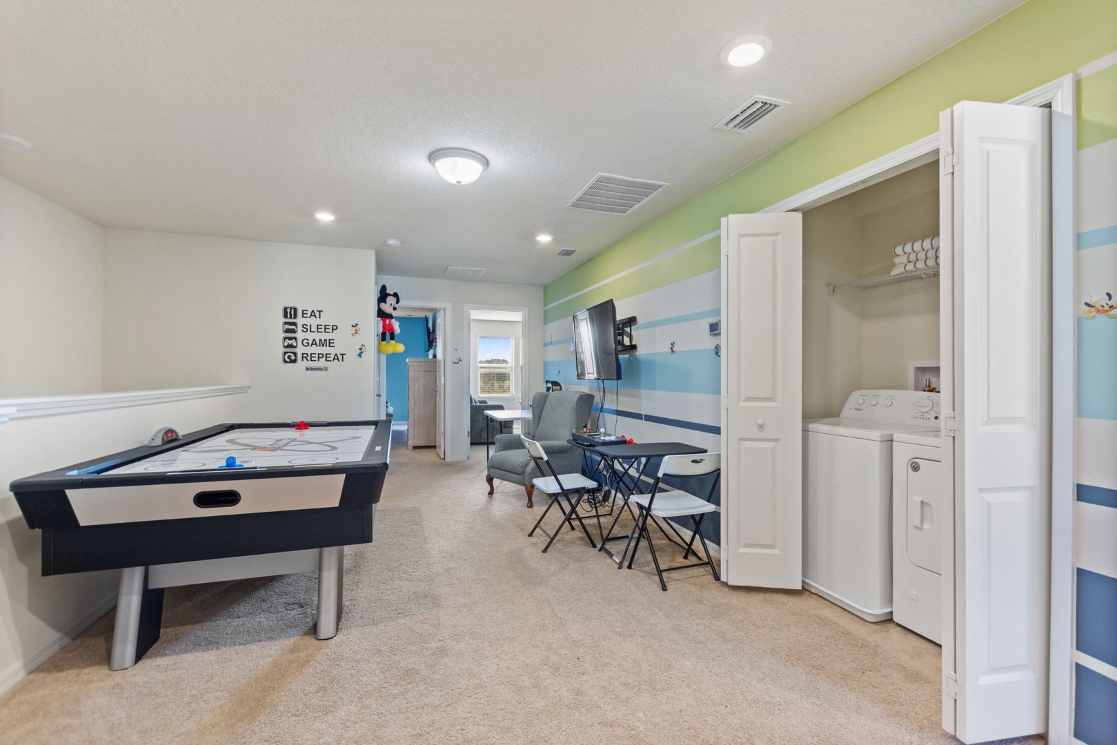 A room with a pool table and a refrigerator.