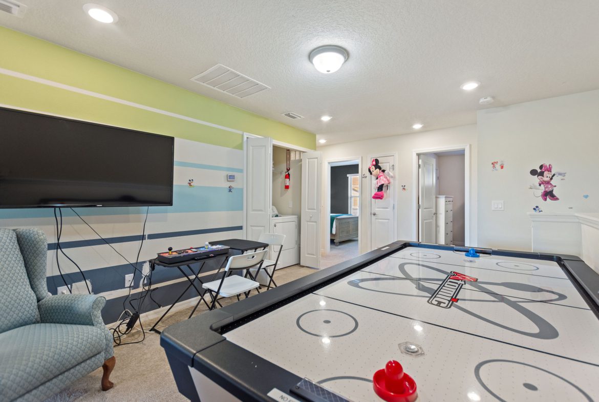 A room with a table and chairs, tv, and air hockey.