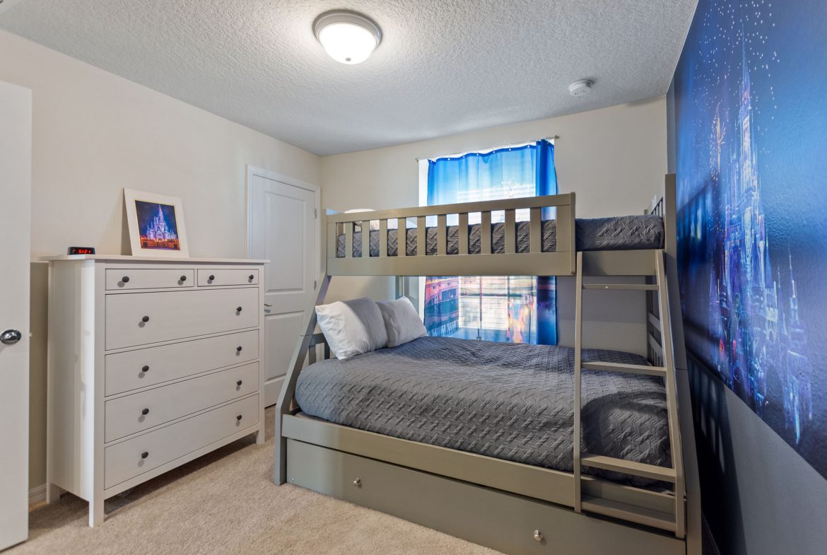 A bedroom with two bunk beds and a dresser.