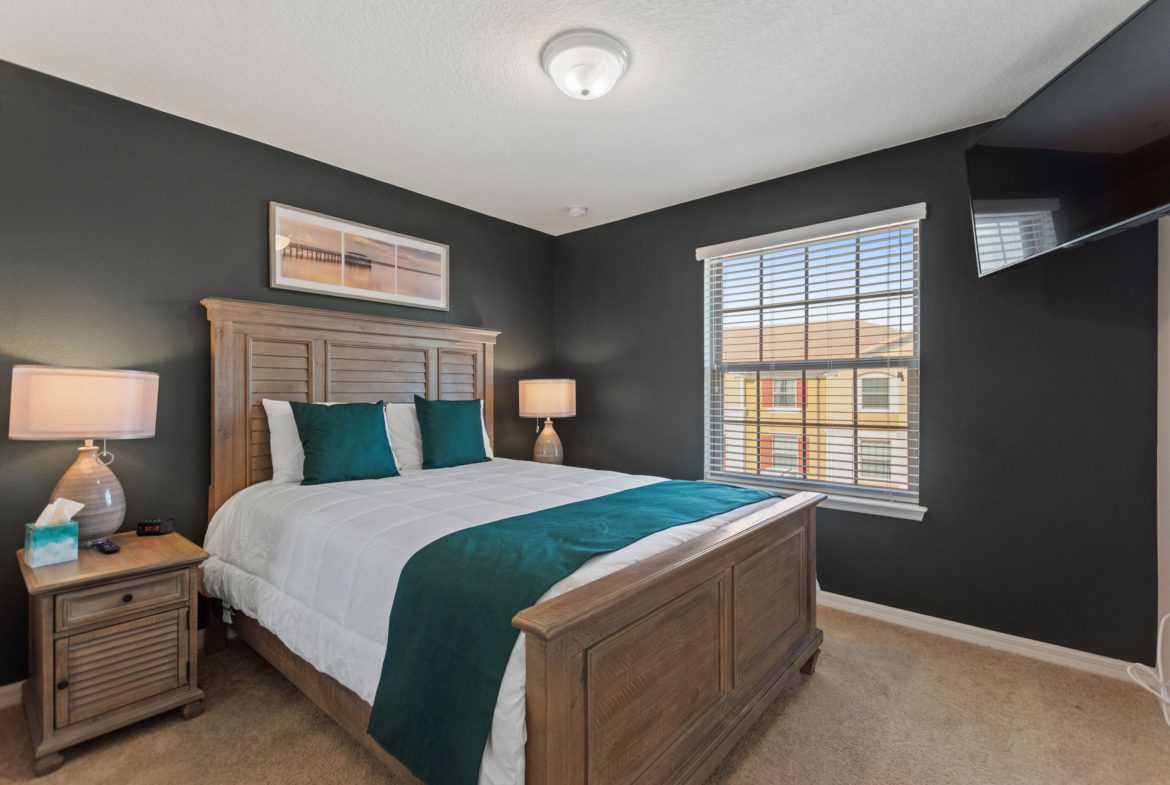 A bedroom with a bed, nightstand and window.