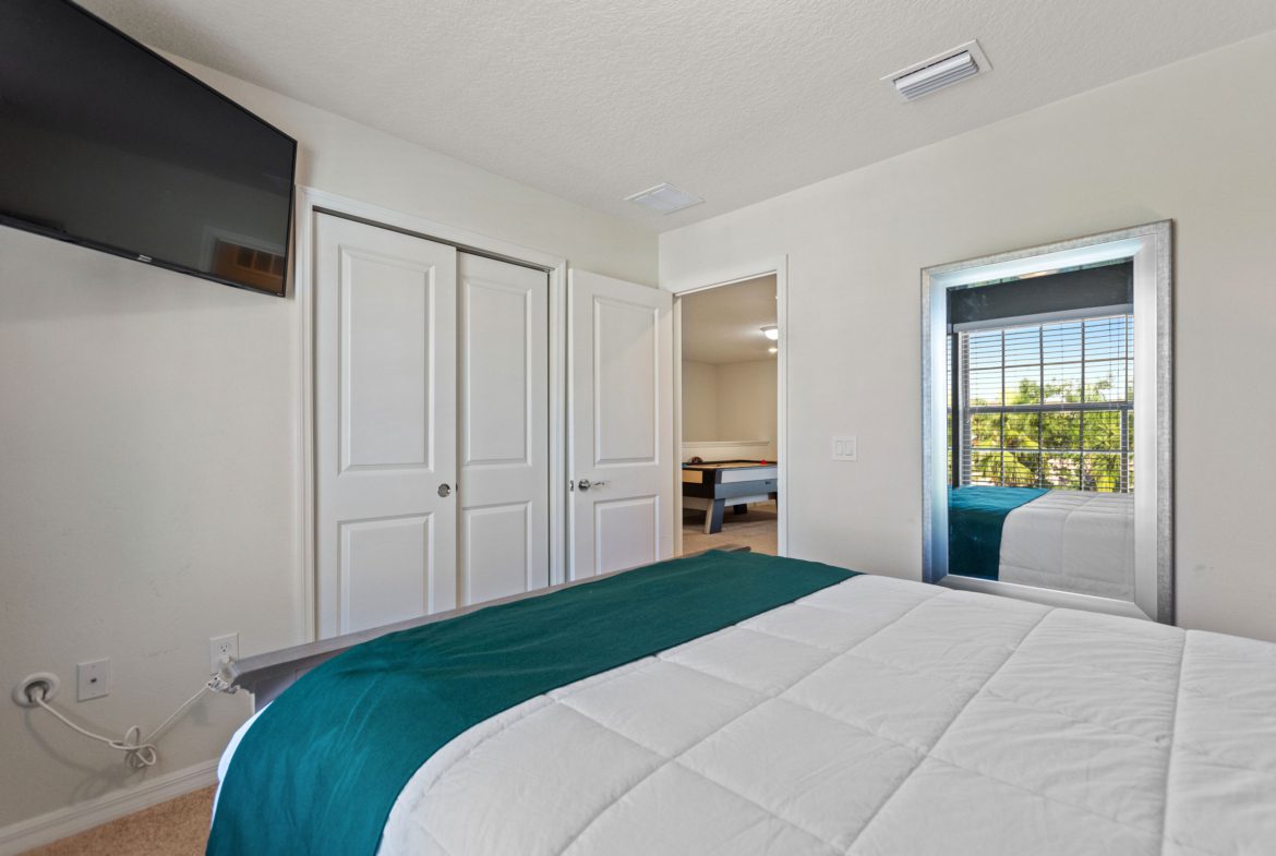 A bedroom with a bed, tv and two closets.