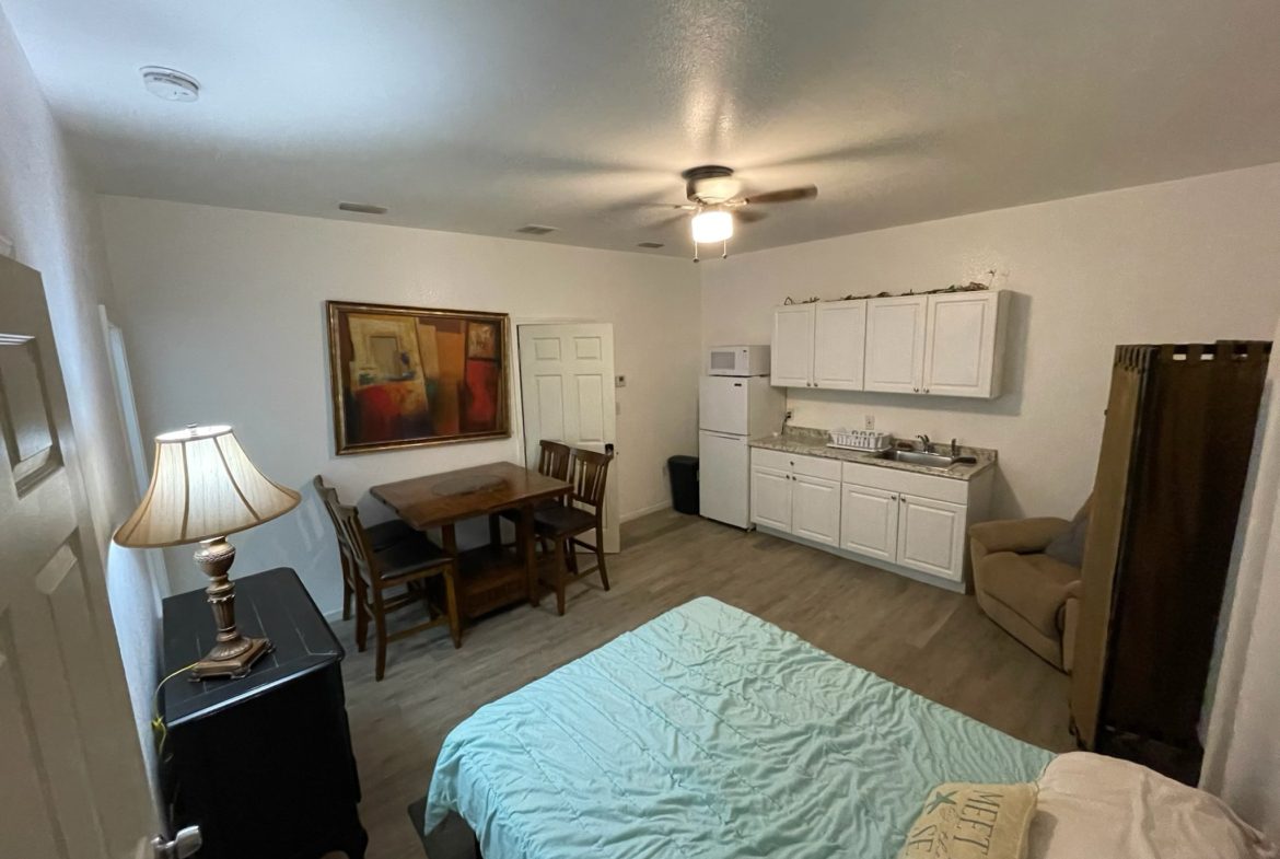 A room with a bed, table and chairs.