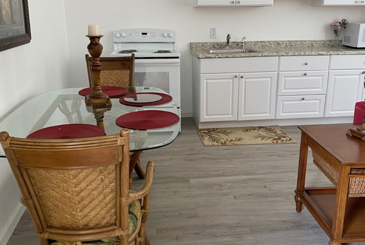 A kitchen with white cabinets and wood floors.