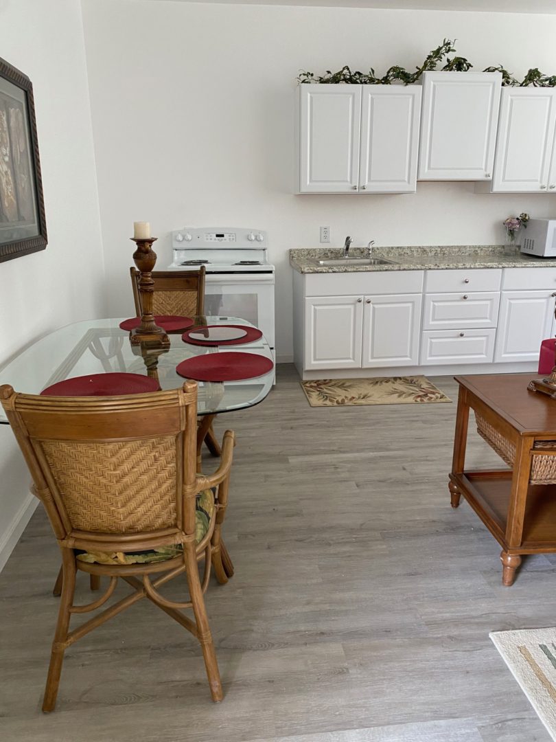 A kitchen with white cabinets and wood floors.