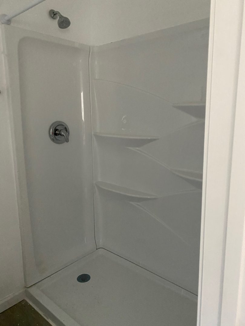 A white shower with shelves and a black handle.