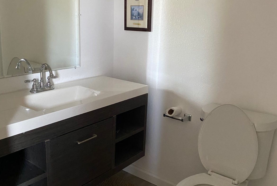 A bathroom with a sink, toilet and mirror.