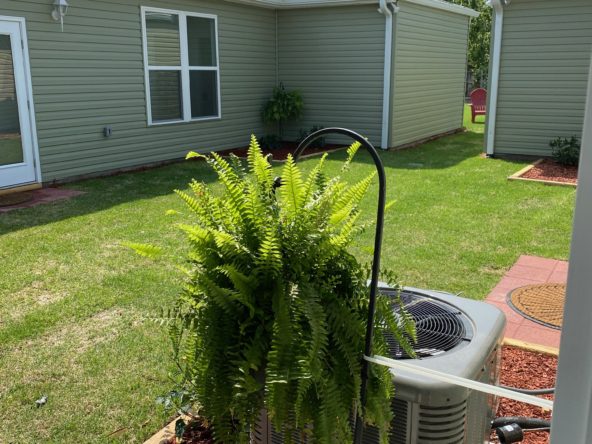 A green house with a large air conditioner.