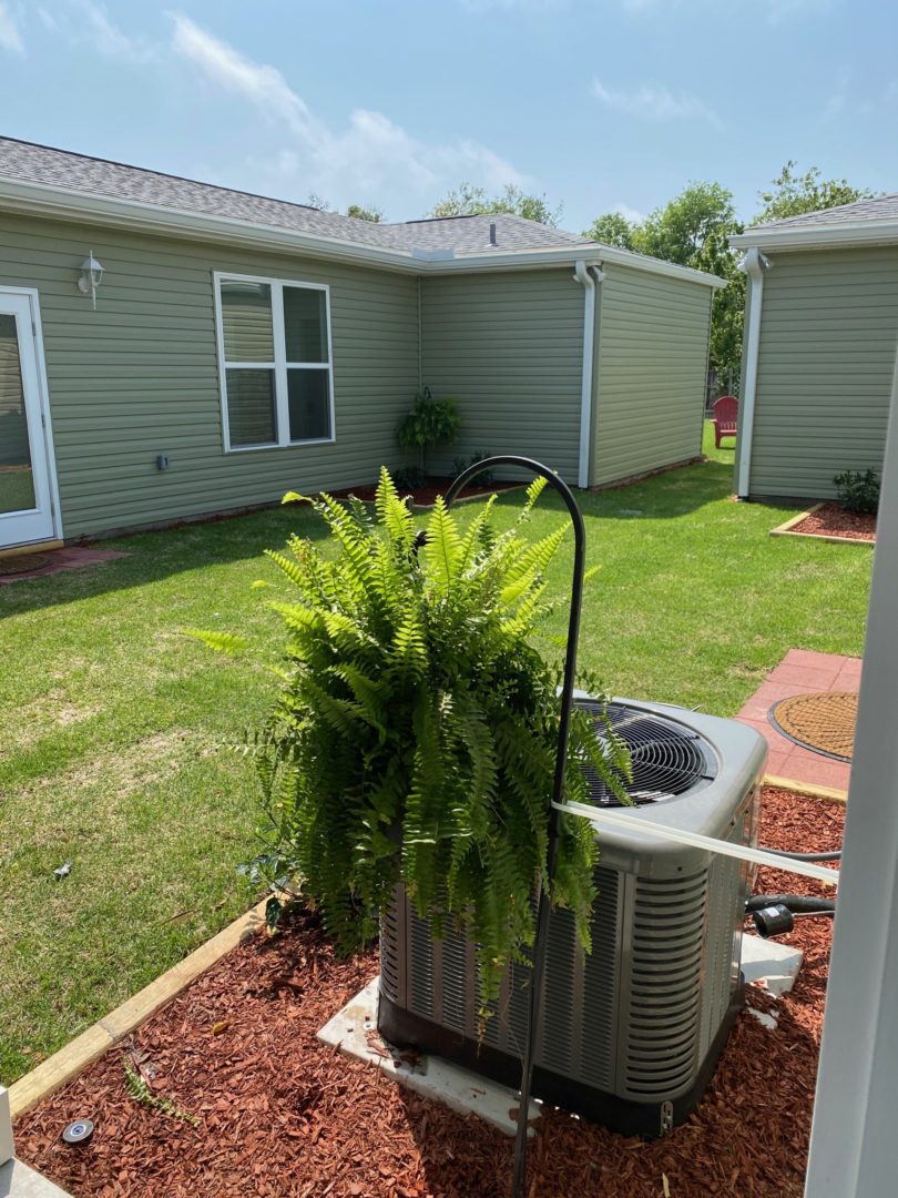 A green house with a large air conditioner.