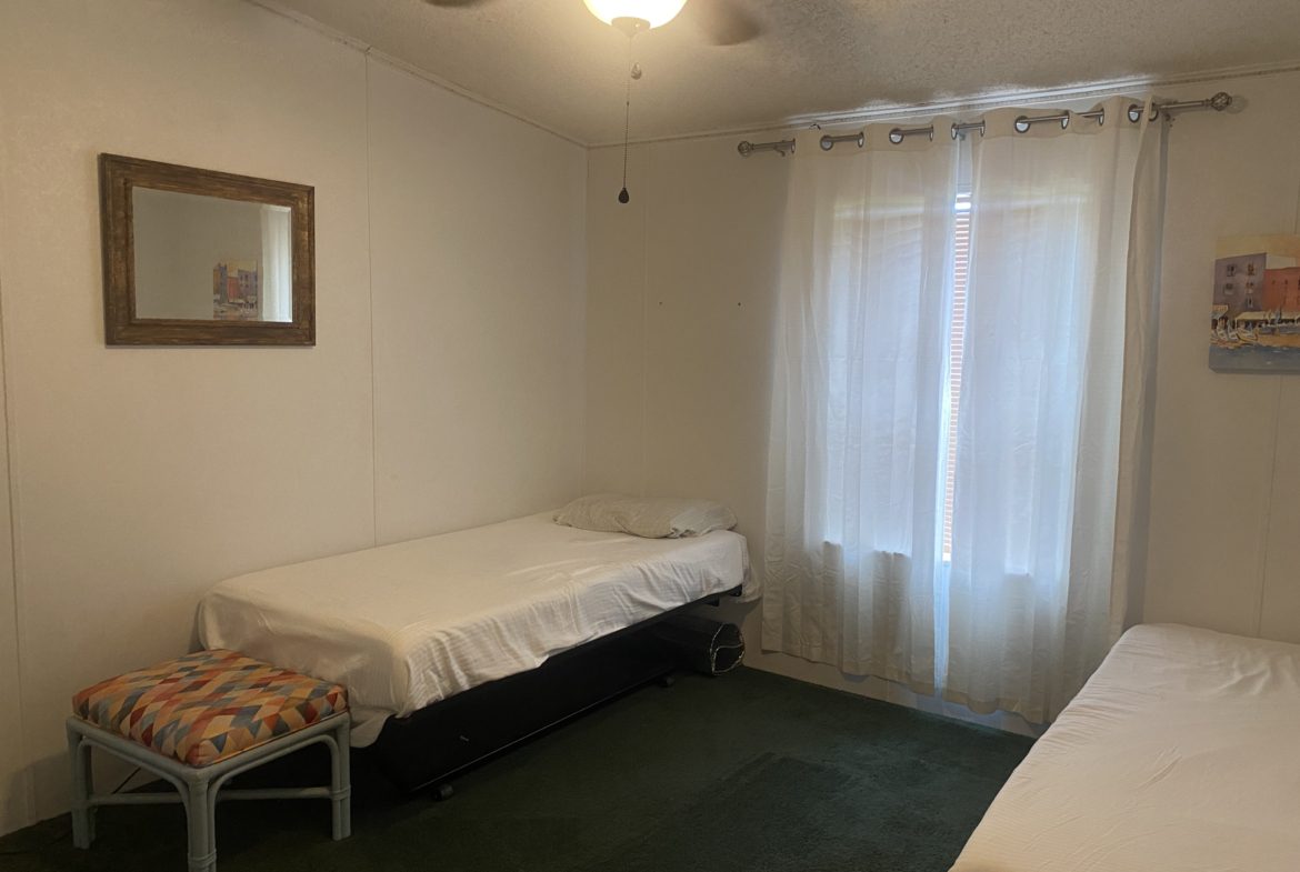 Two beds in a bedroom with a window.