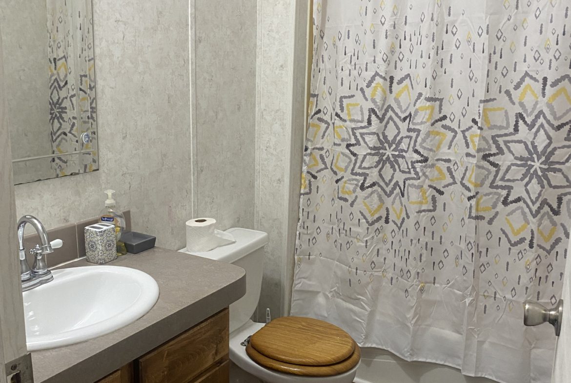 Bathroom with a toilet, sink, and shower.