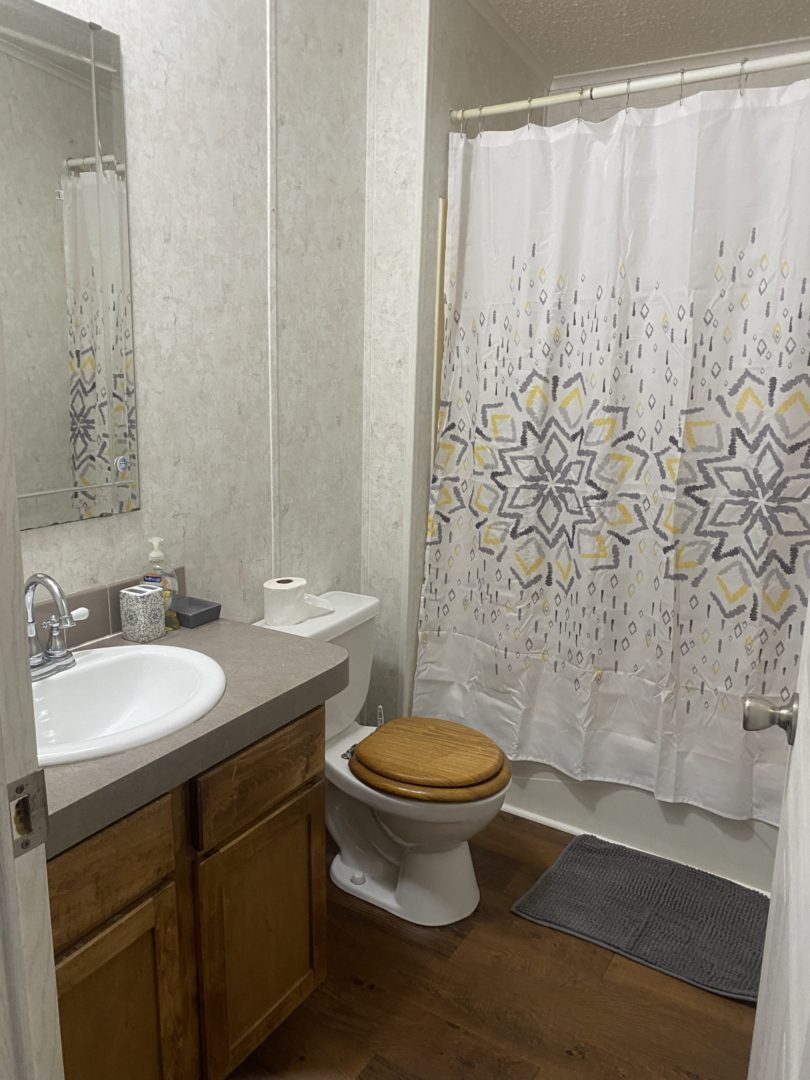 Bathroom with a toilet, sink, and shower.