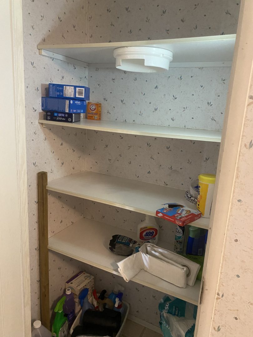 White shelves in a pantry with cleaning supplies.